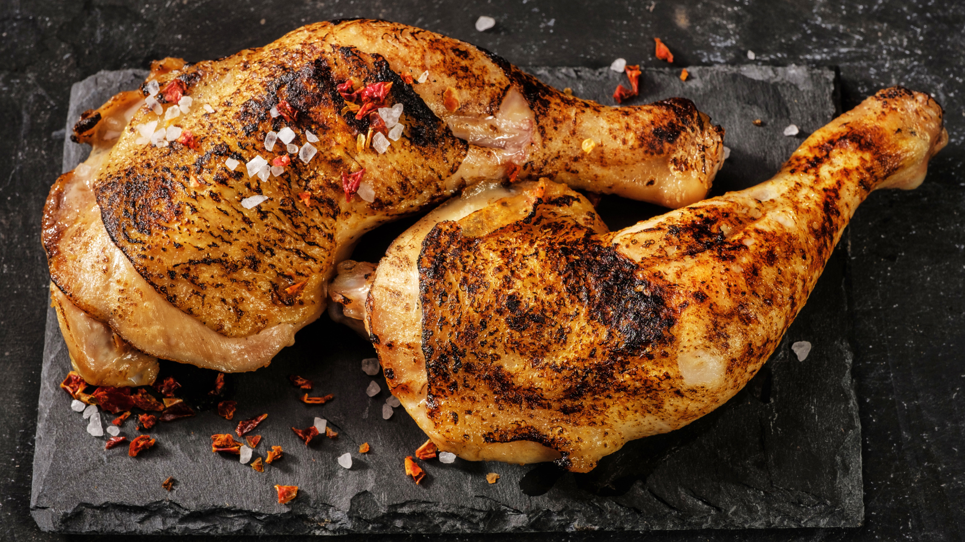 Два запеченных куриных окорочка на черном фоне