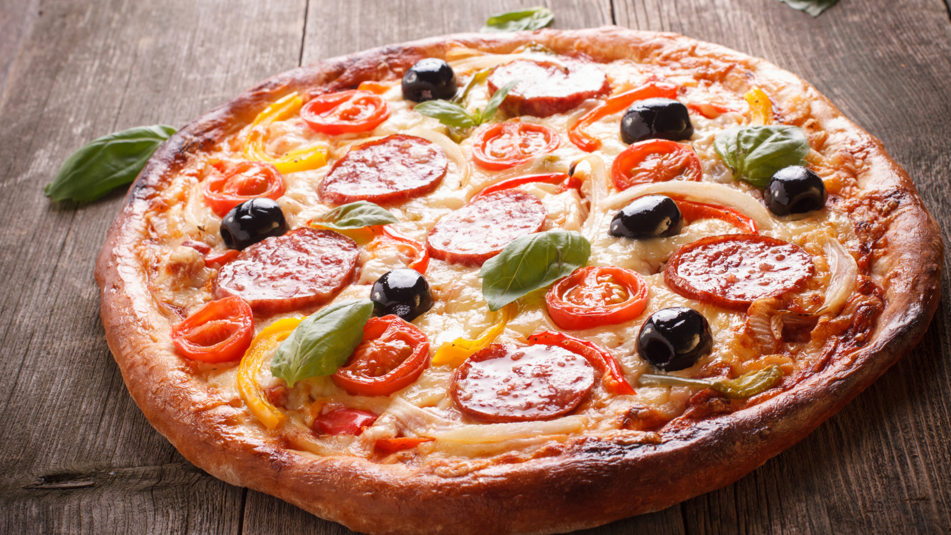 Румяная пицца с колбасой, помидорами, оливками и сыром