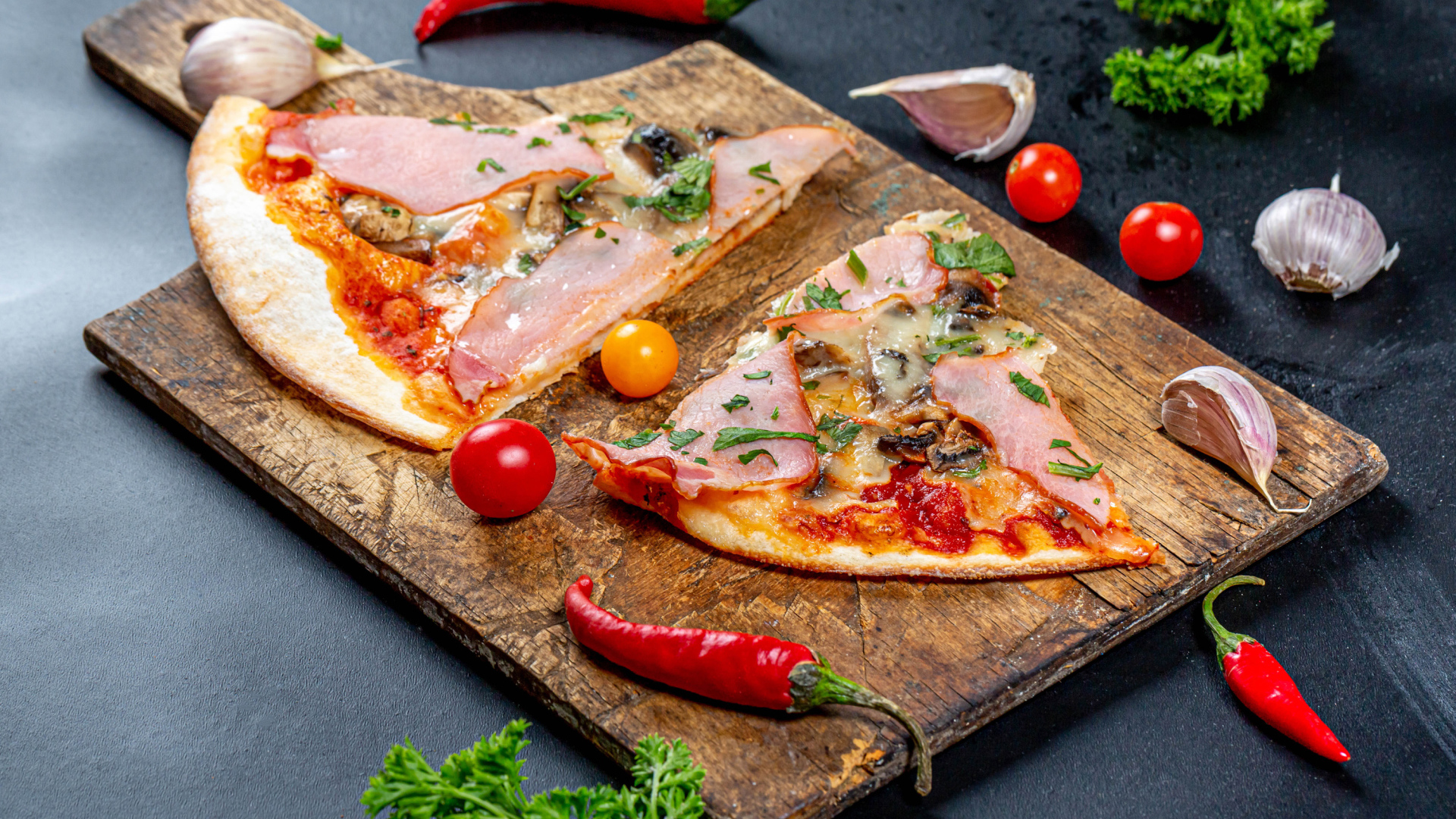 Два куска пиццы на разделочной доске с красным перцем и чесноком