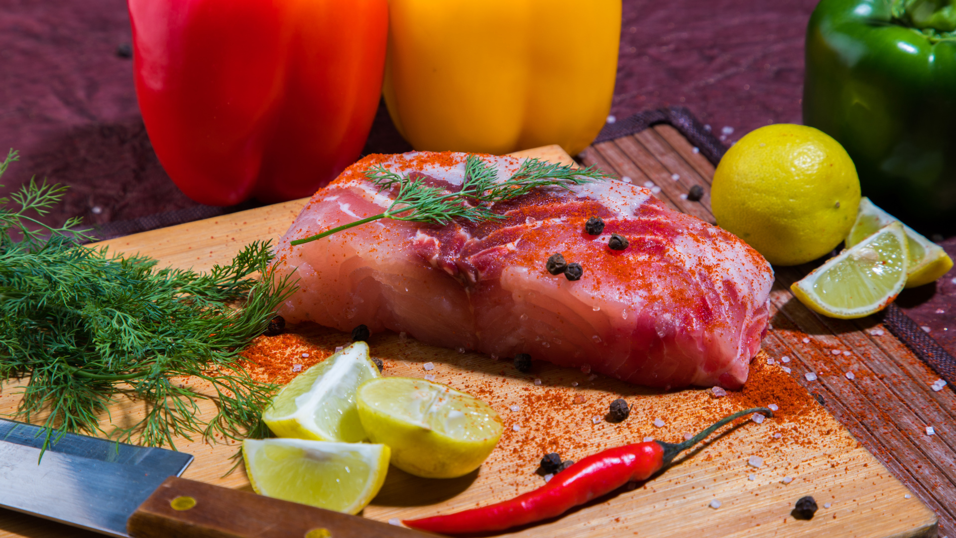 Кусок сырой рыбы на разделочной доске со специями, лимоном и болгарским перцем