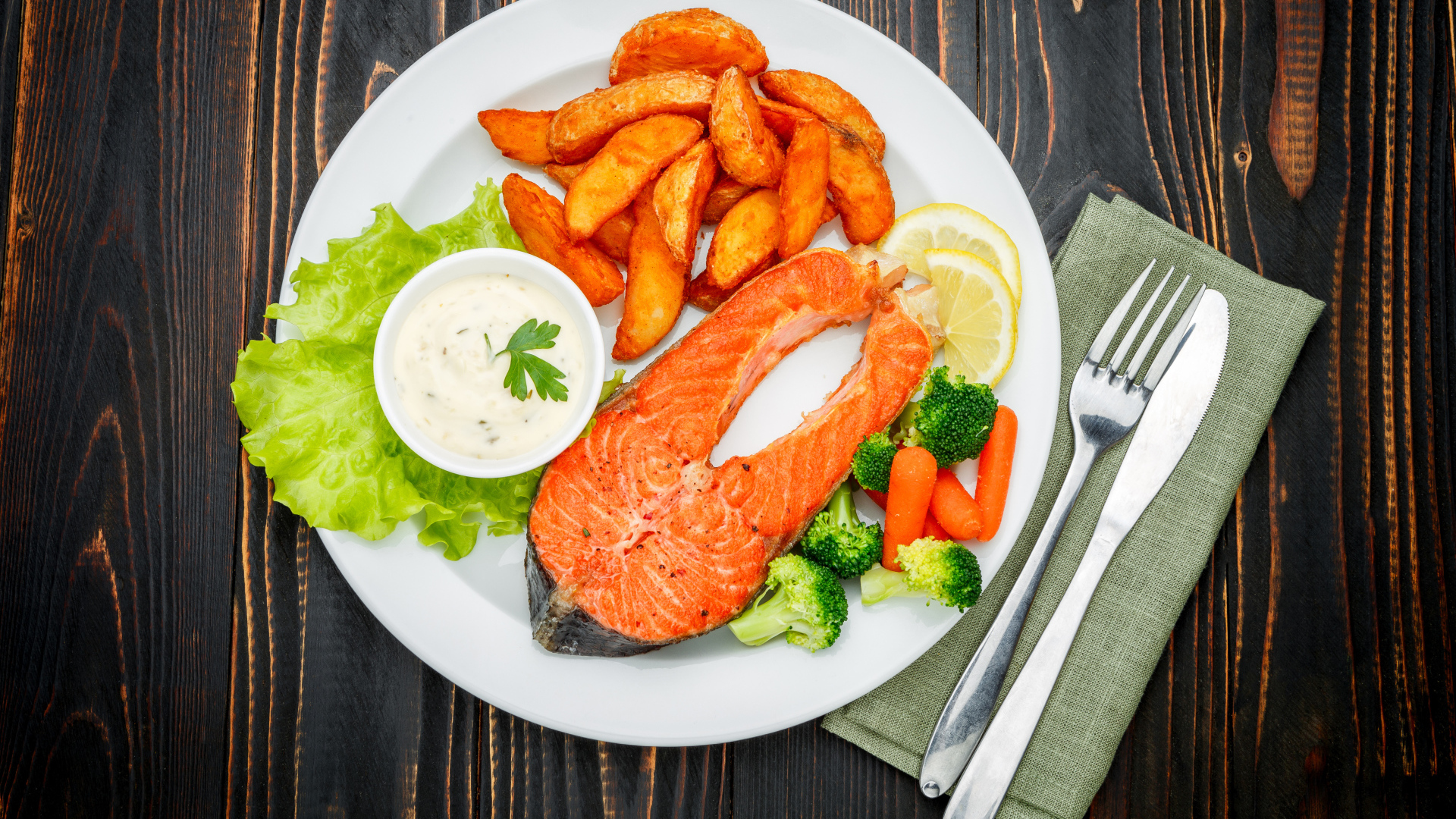 Кусок красной рыбы на тарелке с картофелем и соусом