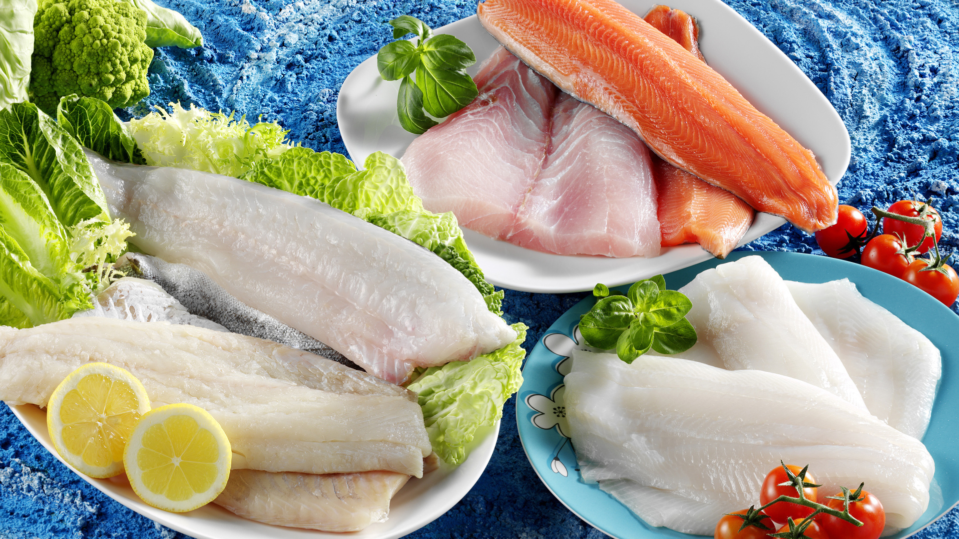 Филе рыбы на тарелках с помидорами и листьями салата