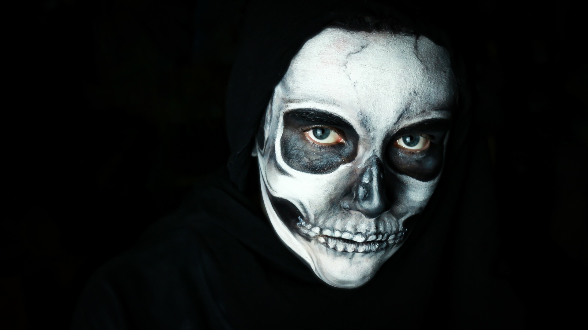 Девушка с маской с грима на лице на черном фоне