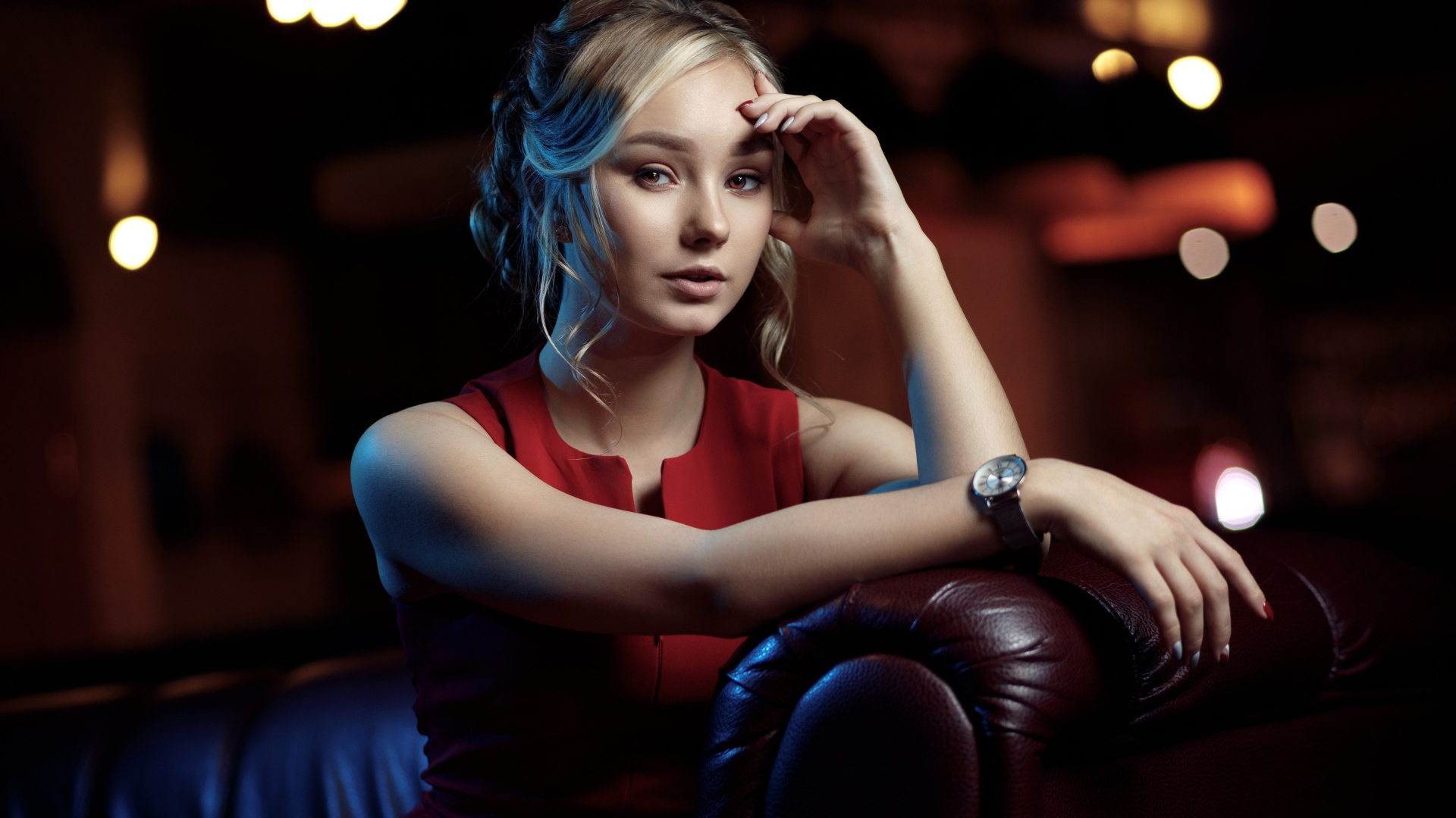 Красивая девушка с часами на руке сидит в кресле