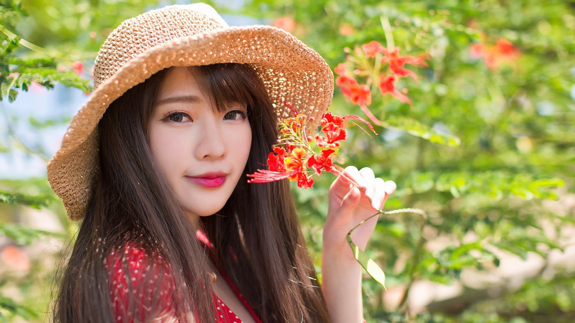 Девушка азиатка в шляпе с красным цветком