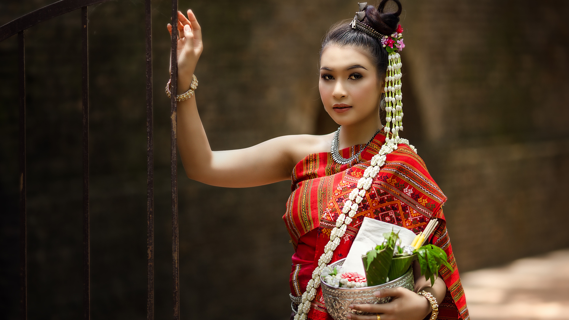 Девушка азиатка в костюме стоит у железных ворот