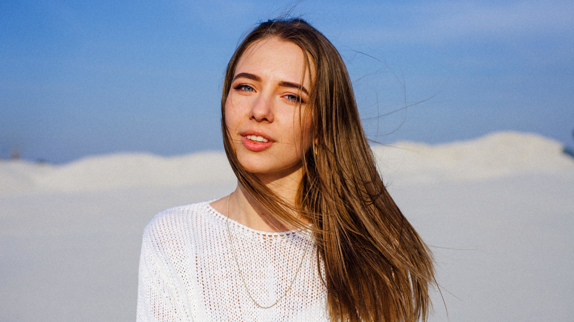 Красивая голубоглазая девушка в белом свитере на фоне голубого неба