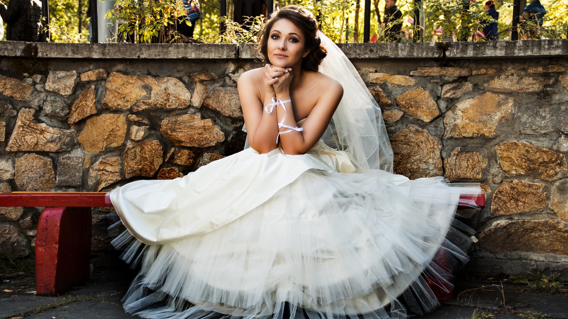 Красивая невеста в белом платье сидит на лавке