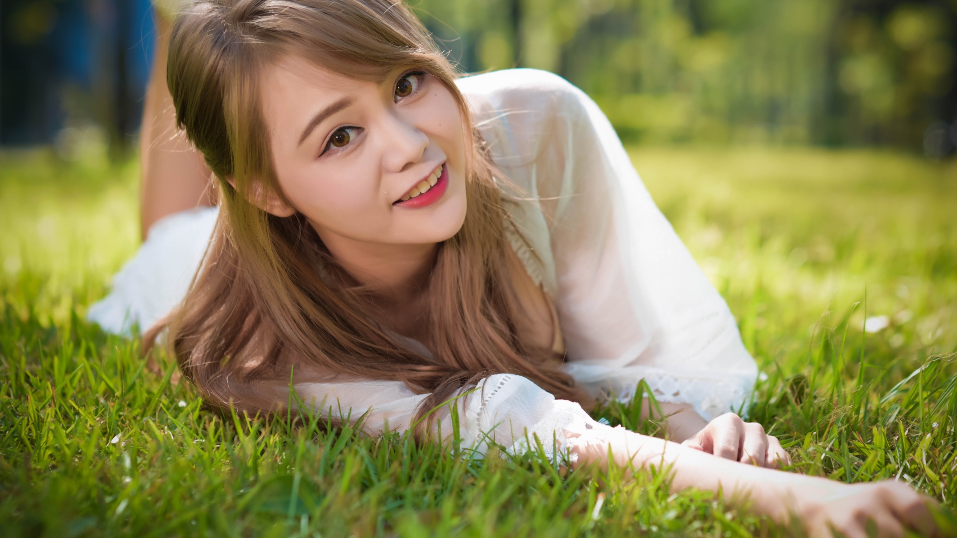 Красивая кареглазая девушка азиатка лежит на зеленой траве