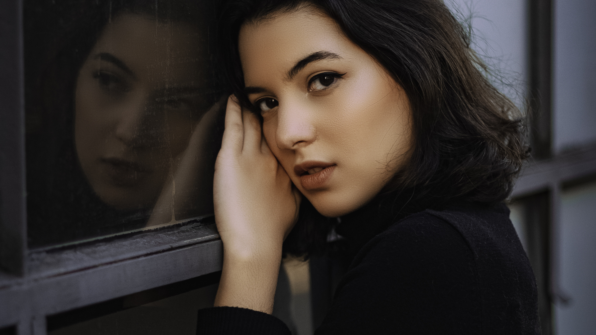 Красивая кареглазая девушка стоит у окна