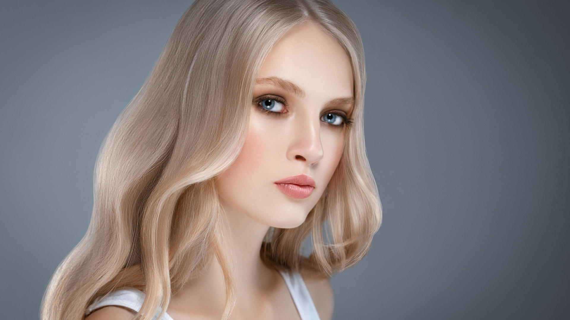 Красивая нежная голубоглазая блондинка на сером фоне