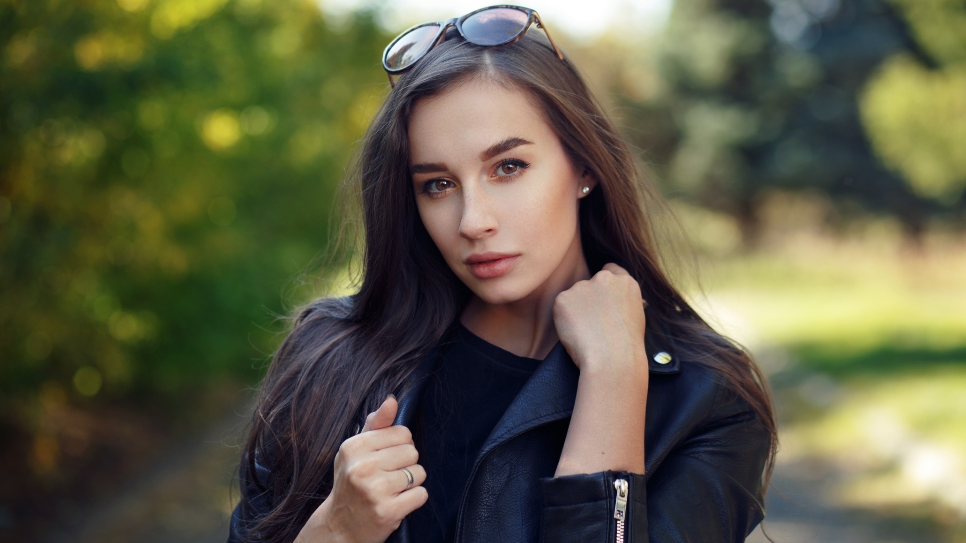 Красивая девушка в черной куртке с очками на голове