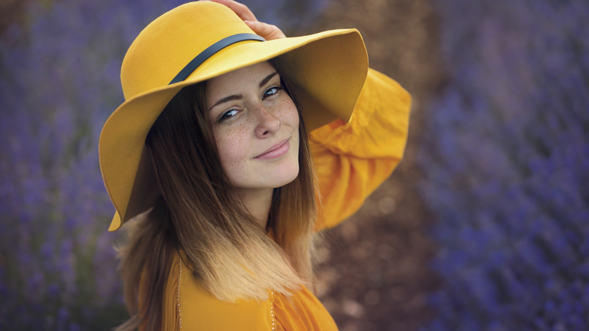 Красивая девушка с веснушками на лице в желтой шляпе