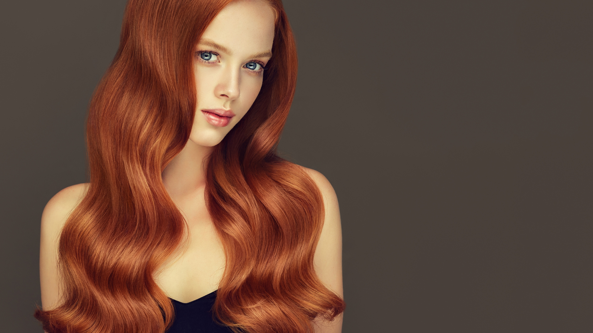 Красивая рыжеволосая голубоглазая девушка на сером фоне