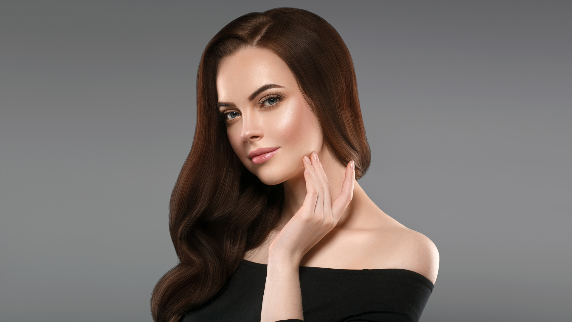 Нежная длинноволосая шатенка в черном платье на сером фоне