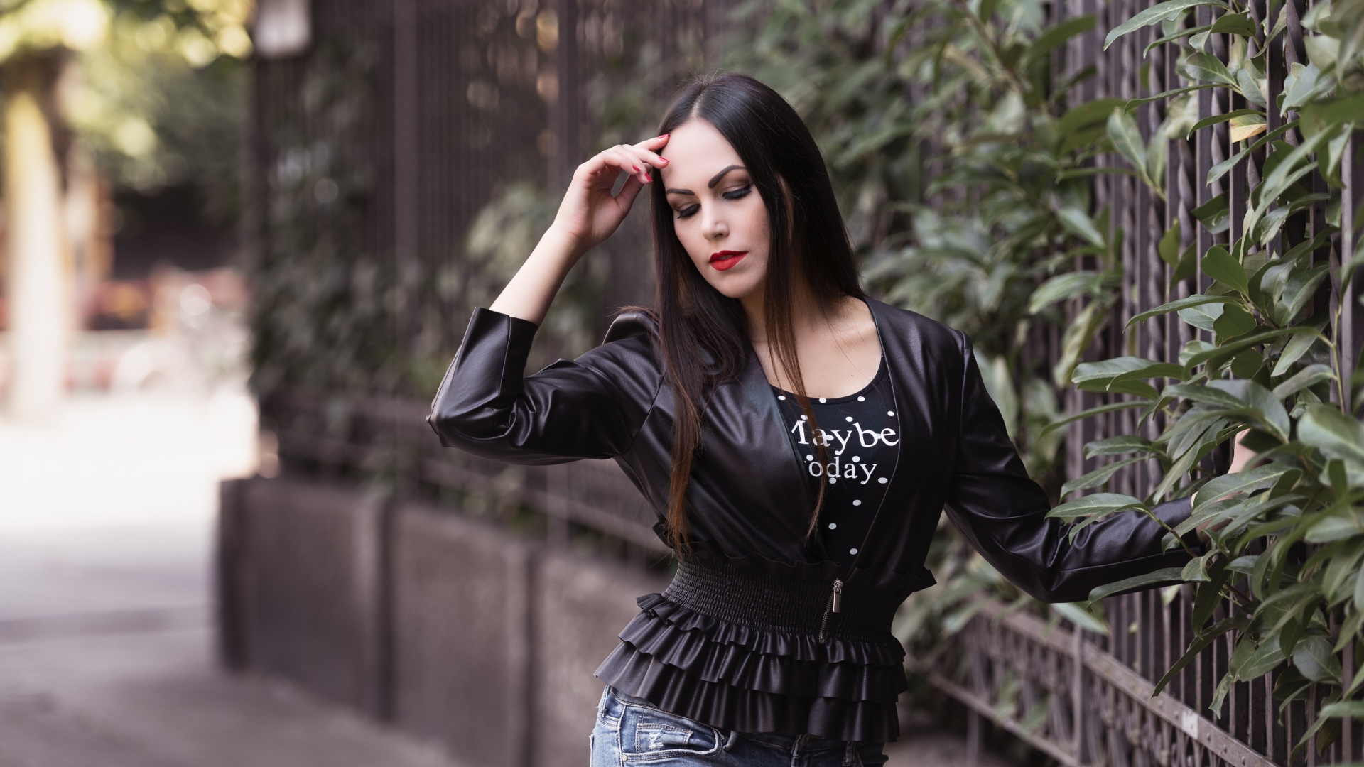 Длинноволосая брюнетка в черной куртке у забора