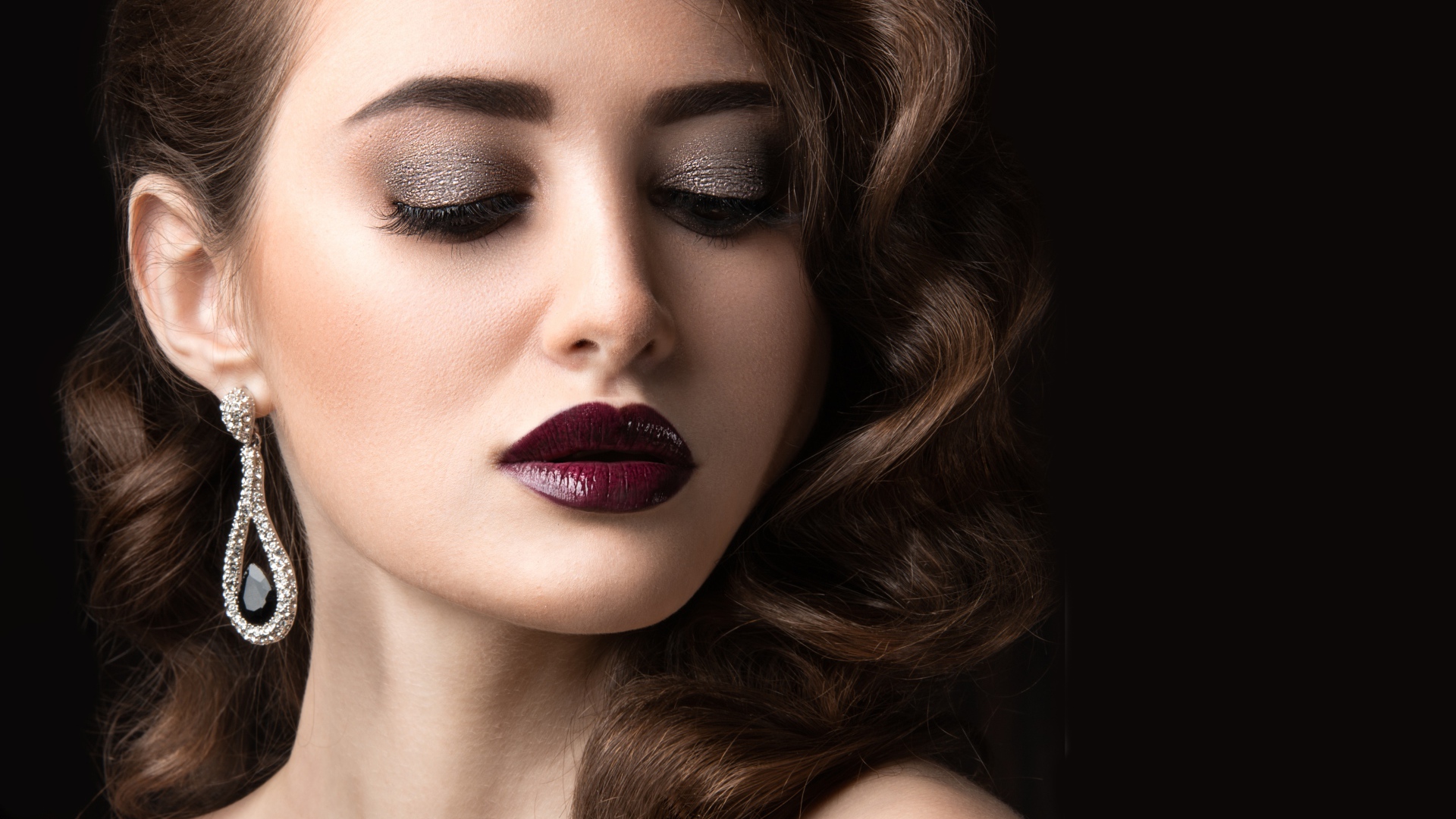 Длинноволосая девушка с ярким макияжем на черном фоне