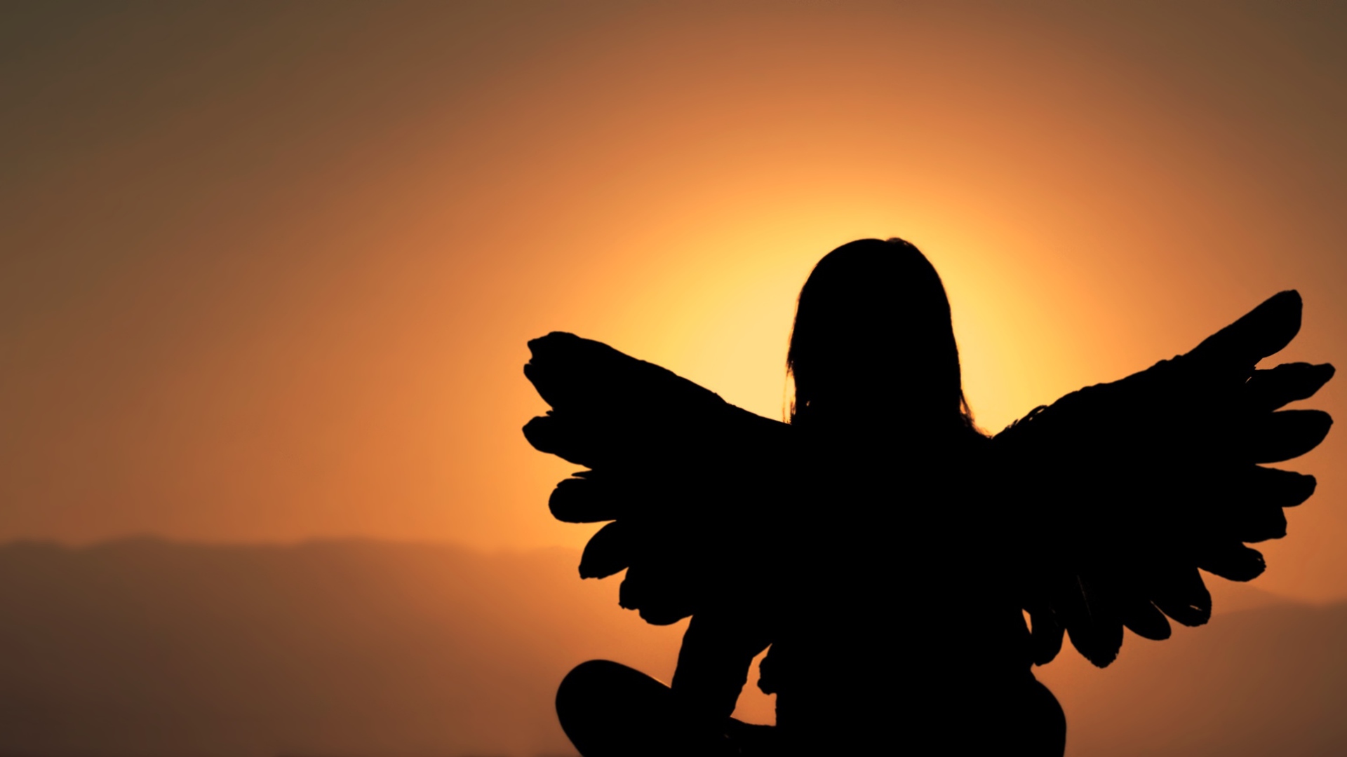 Силуэт девушки с крыльями ангела на фоне заката
