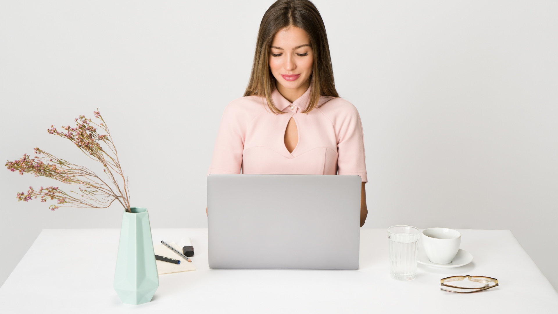 Умная девушка за ноутбуком на сером фоне