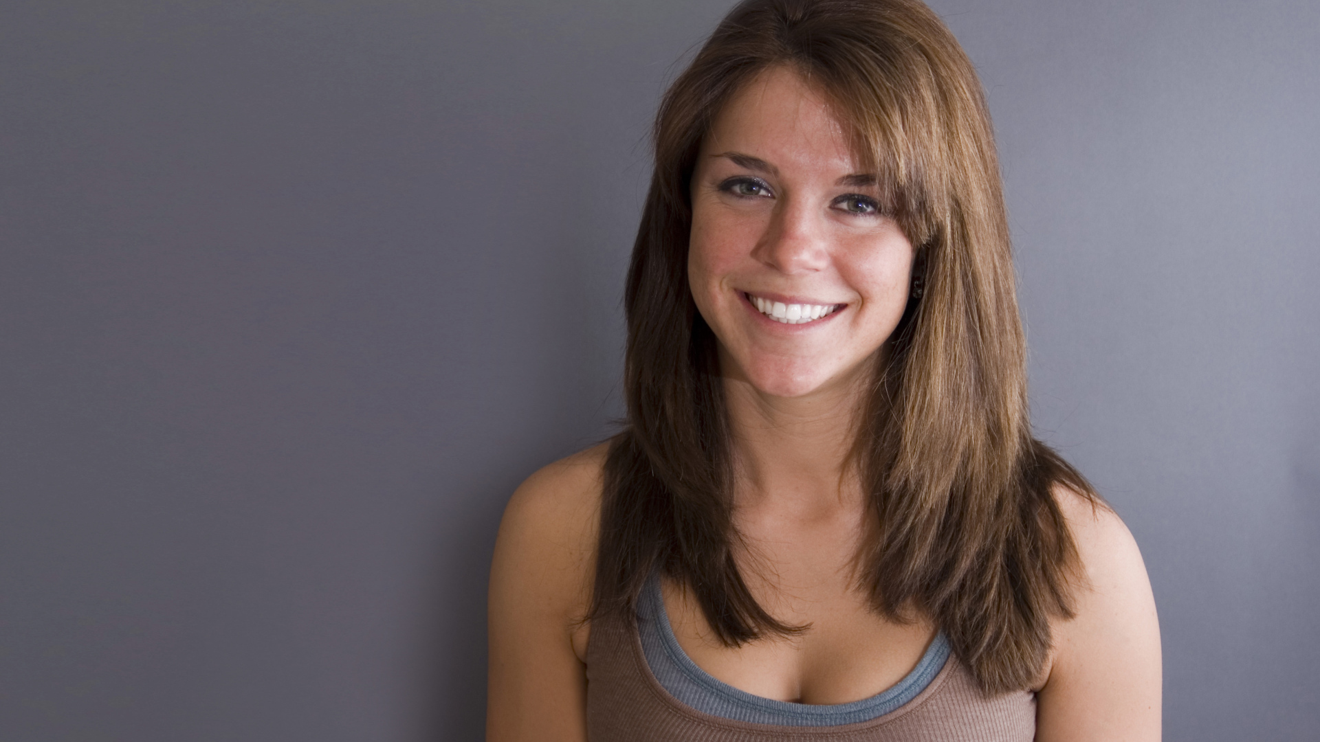 Улыбающаяся милая девушка у серой стены