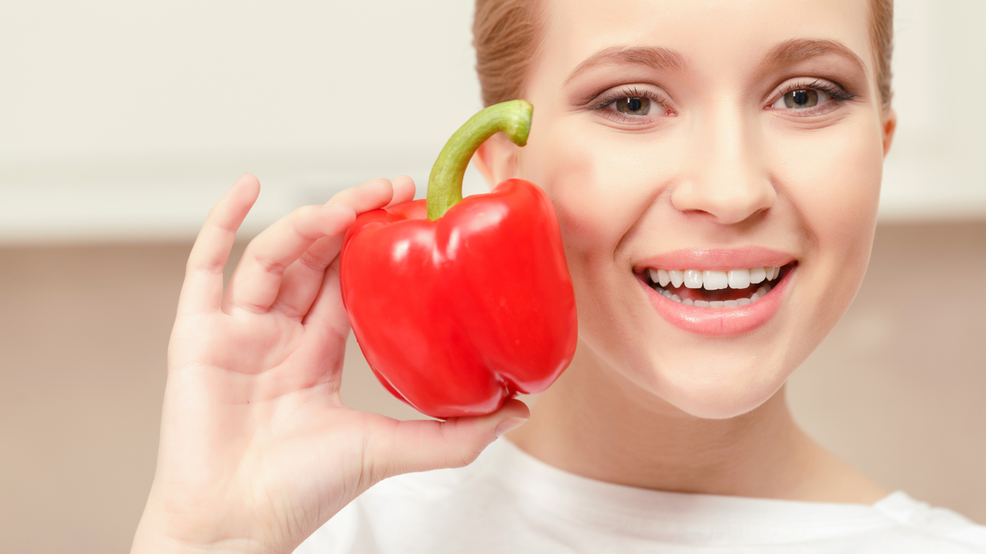 Улыбающаяся девушка с красным сладким перцем в руке