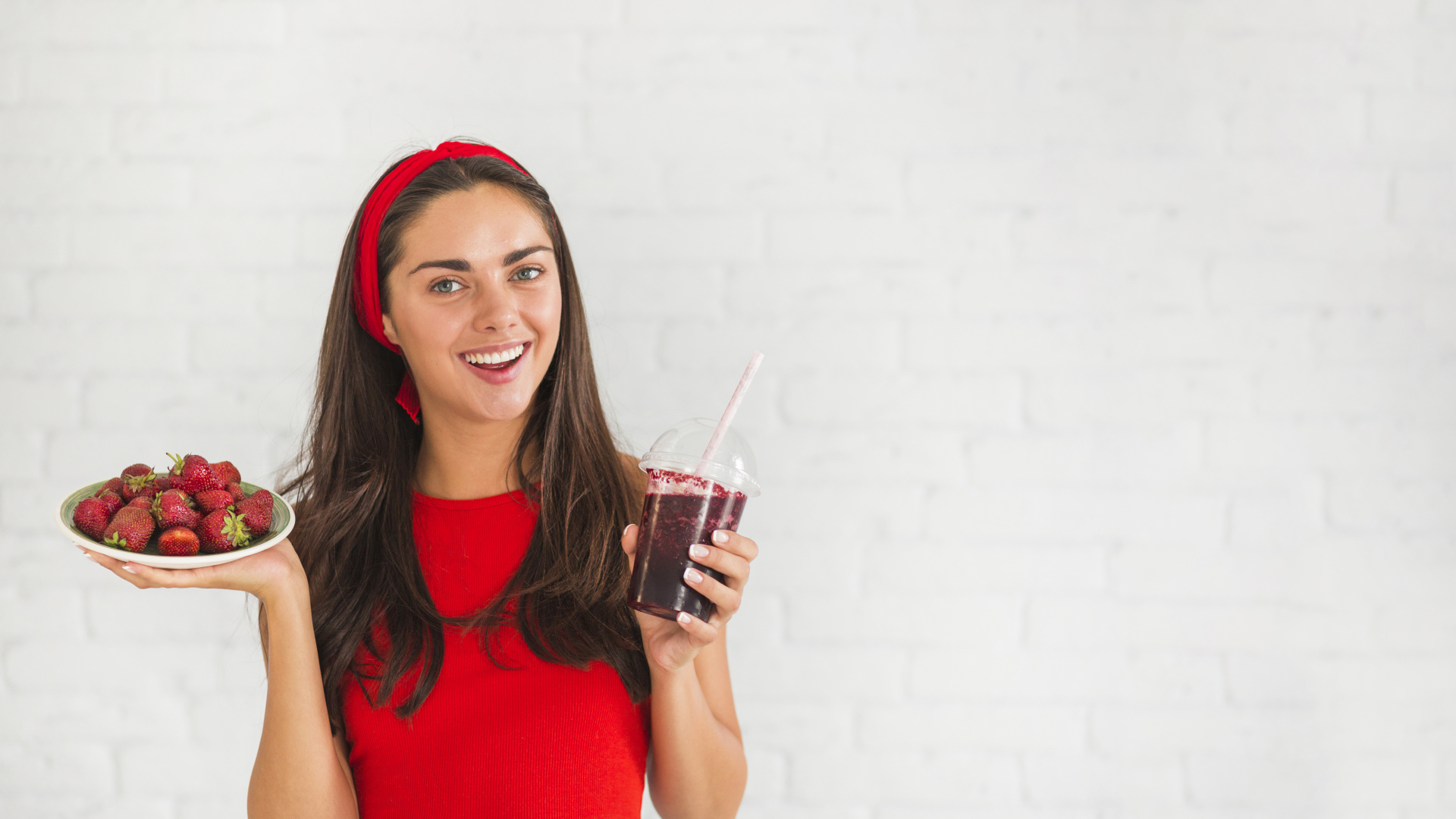 Улыбающаяся девушка с клубникой и смузи в руках