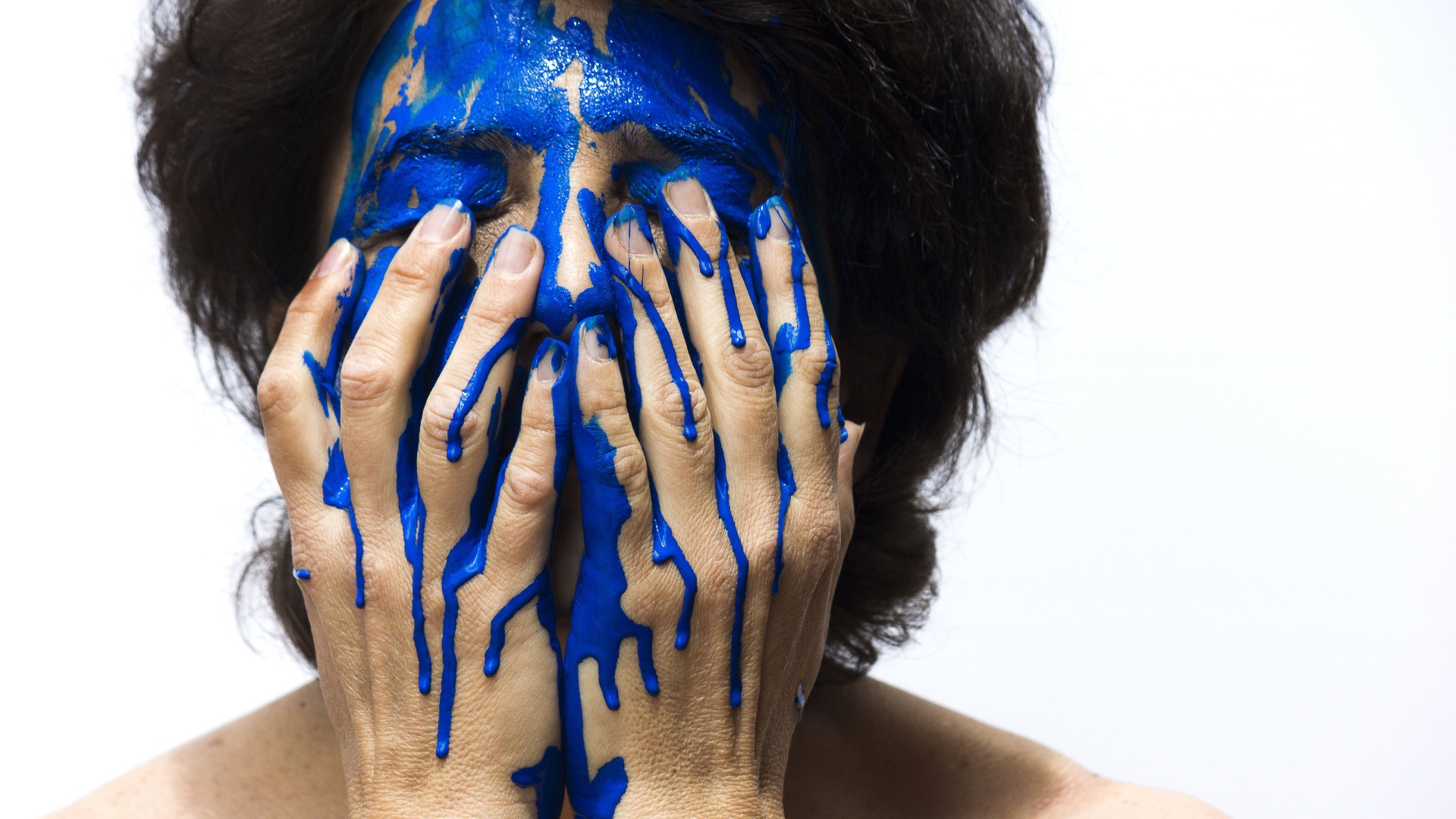 Лицо и руки женщины в синей краске