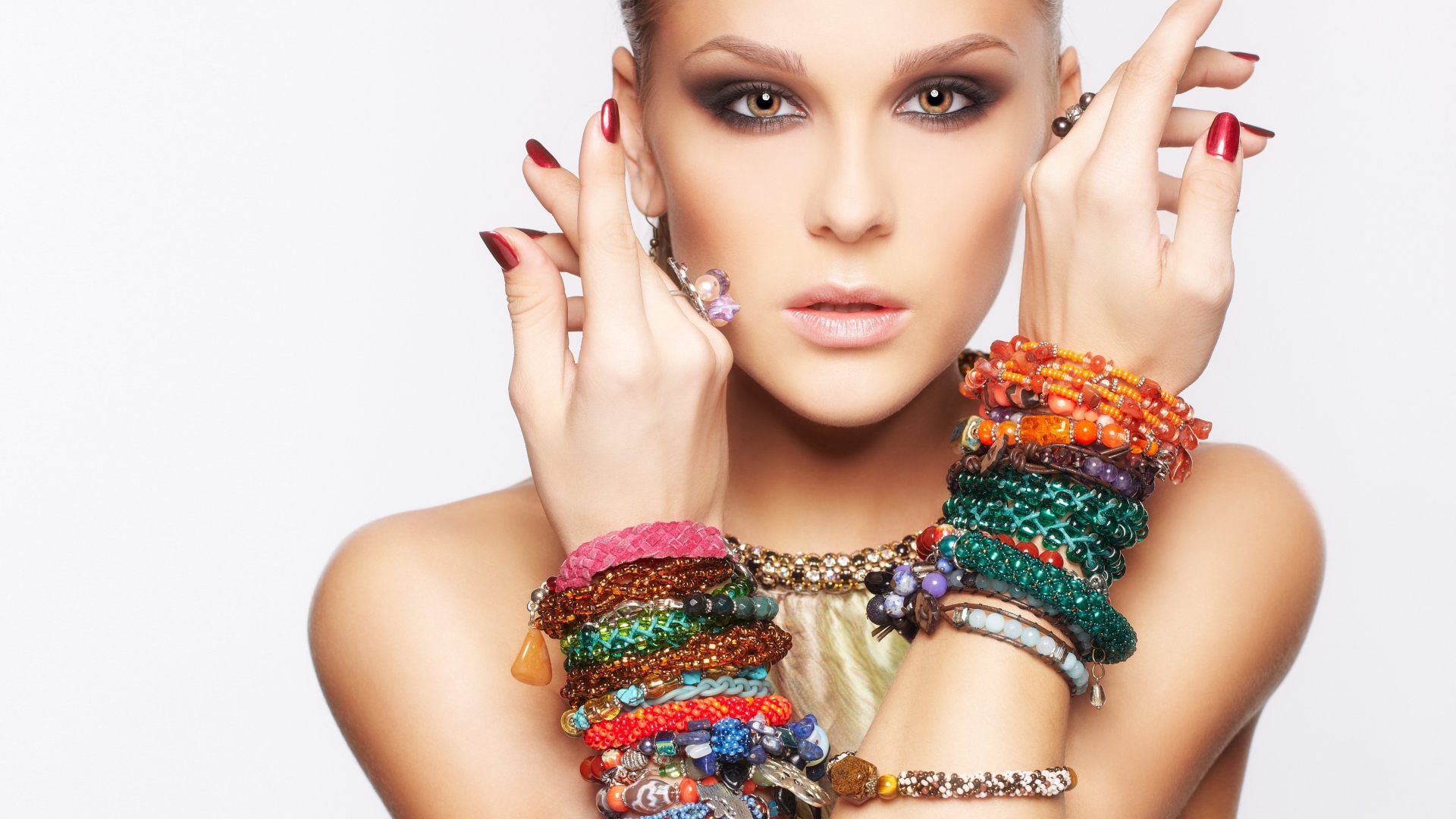 Молодая кареглазая девушка с браслетами на руках на белом фоне