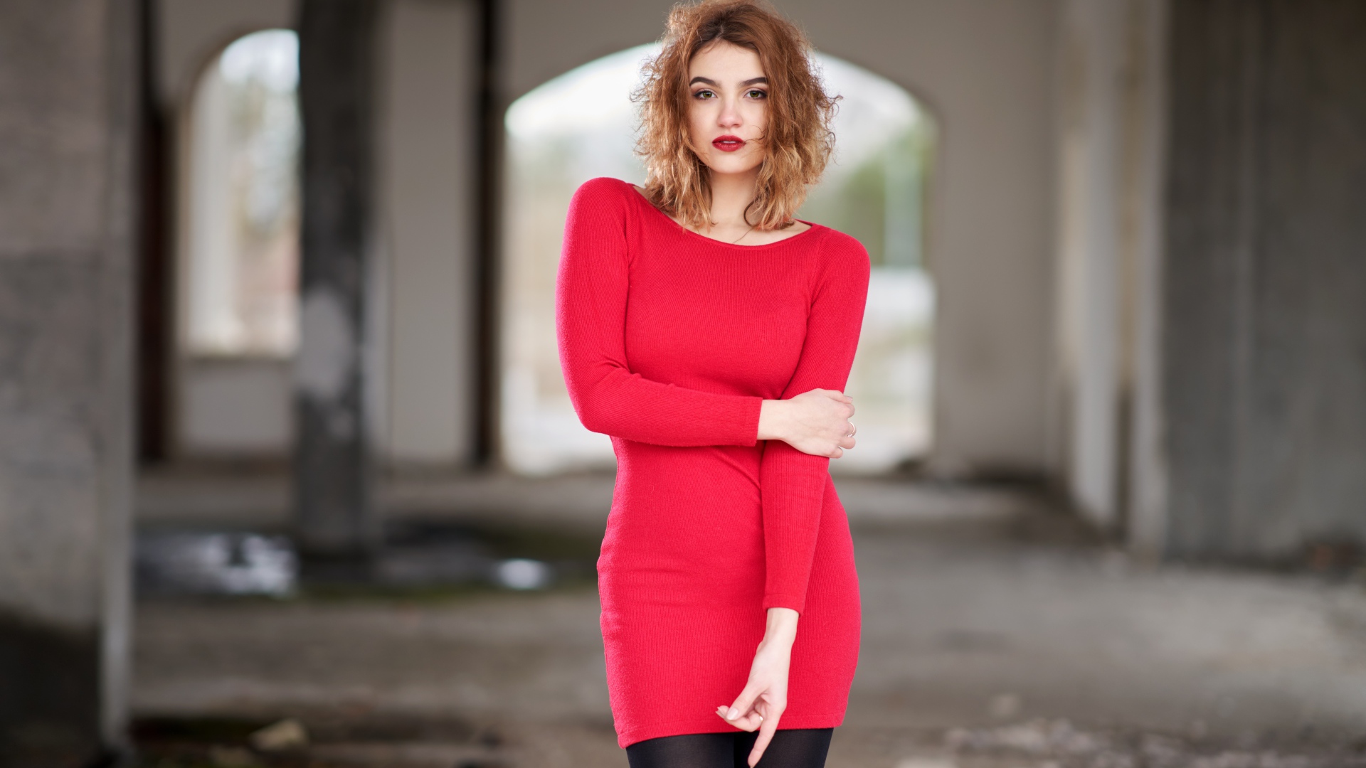 Молодая девушка в красном платье в старом здании