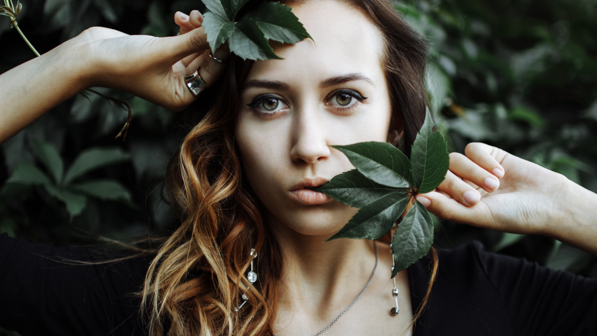 Молодая девушка с зелеными листьями в руках 