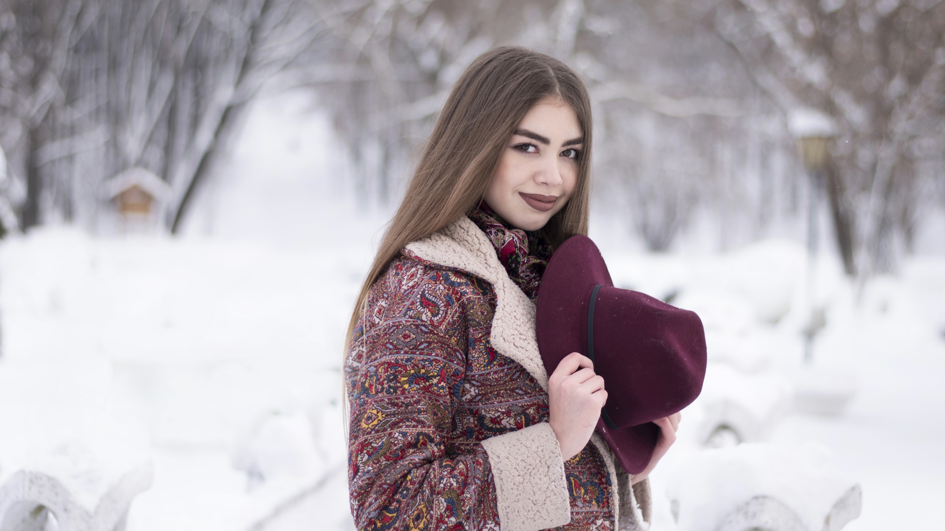 Молодая длинноволосая девушка шатенка с шляпой в руках зимой