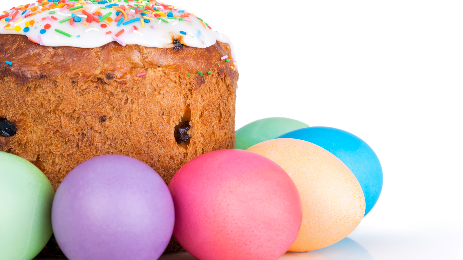 Пасхальный кулич с изюмом на белом фоне с крашеными яйцами 