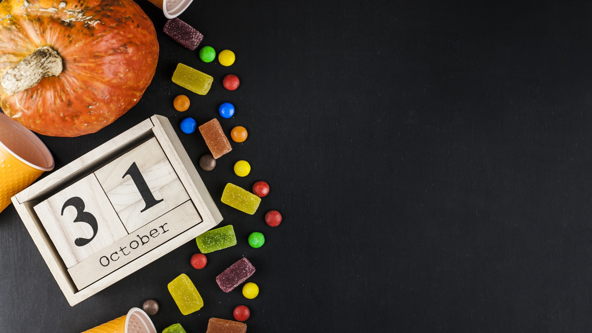 Конфеты, тыква и календарь на сером фоне на Хэллоуин