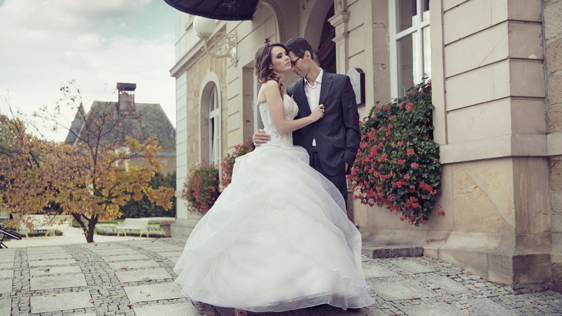 Жених и невеста стоят у здания 