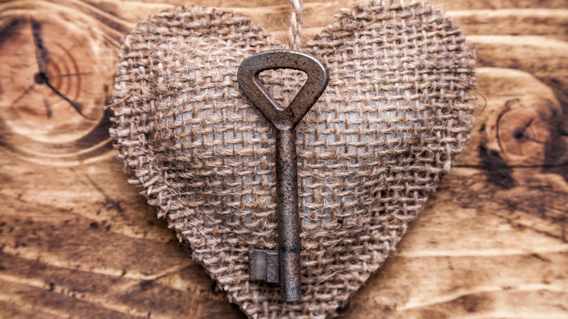 Сердечко из мешковины с ключом на деревянном фоне
