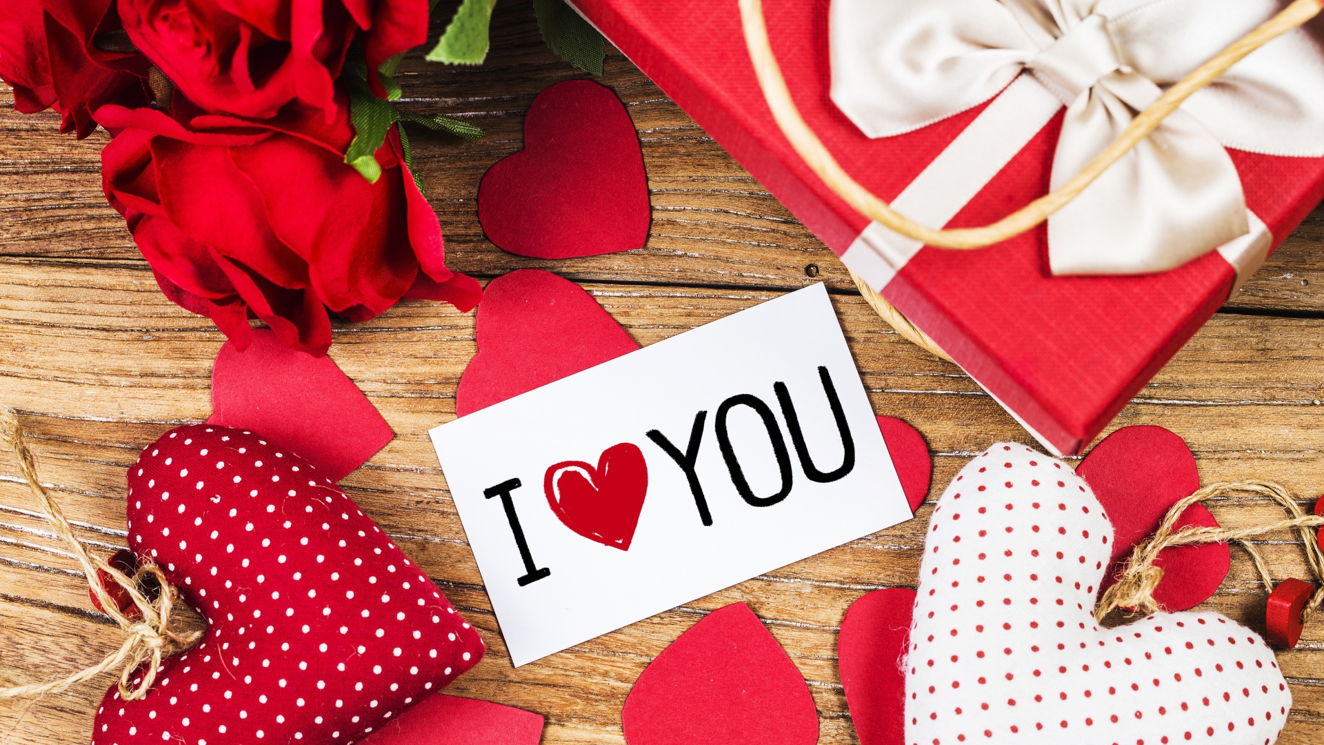 Сердечки, цветы и подарок на столе с запиской