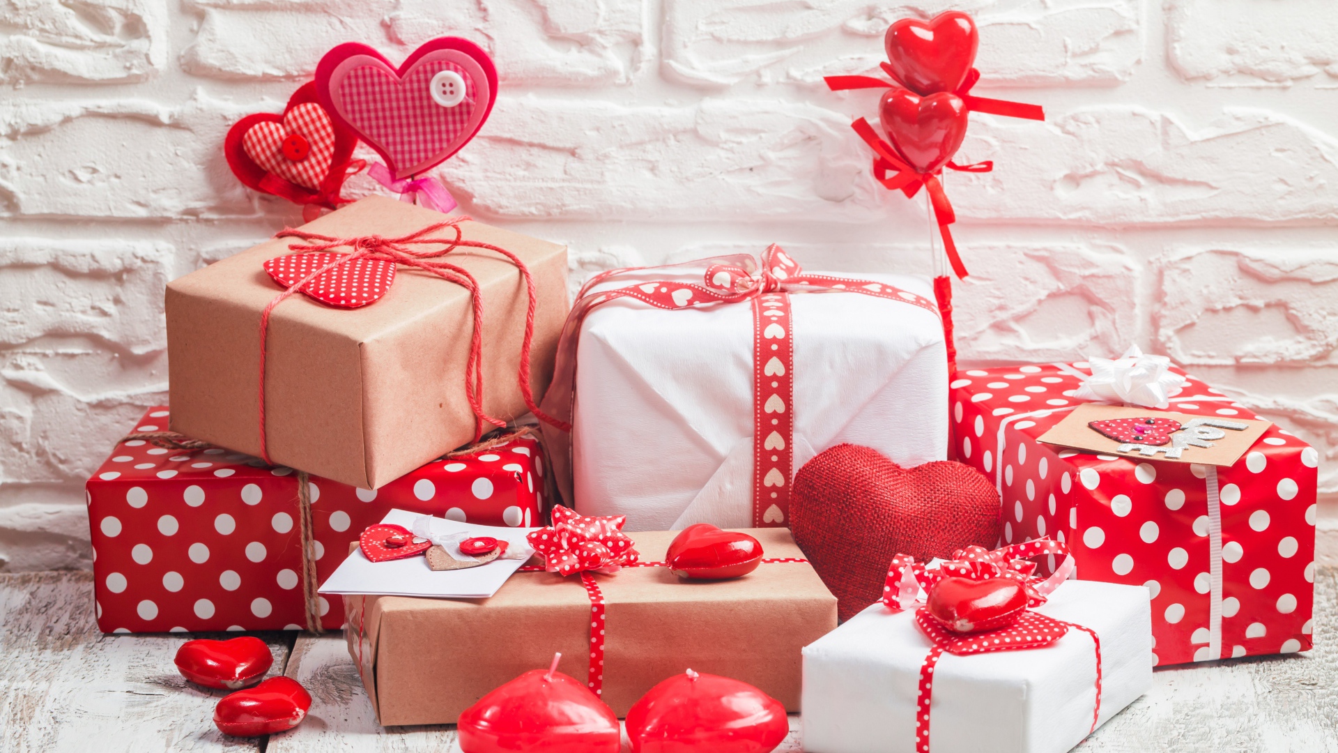Много  подарочных коробок с сердечками на фоне стены