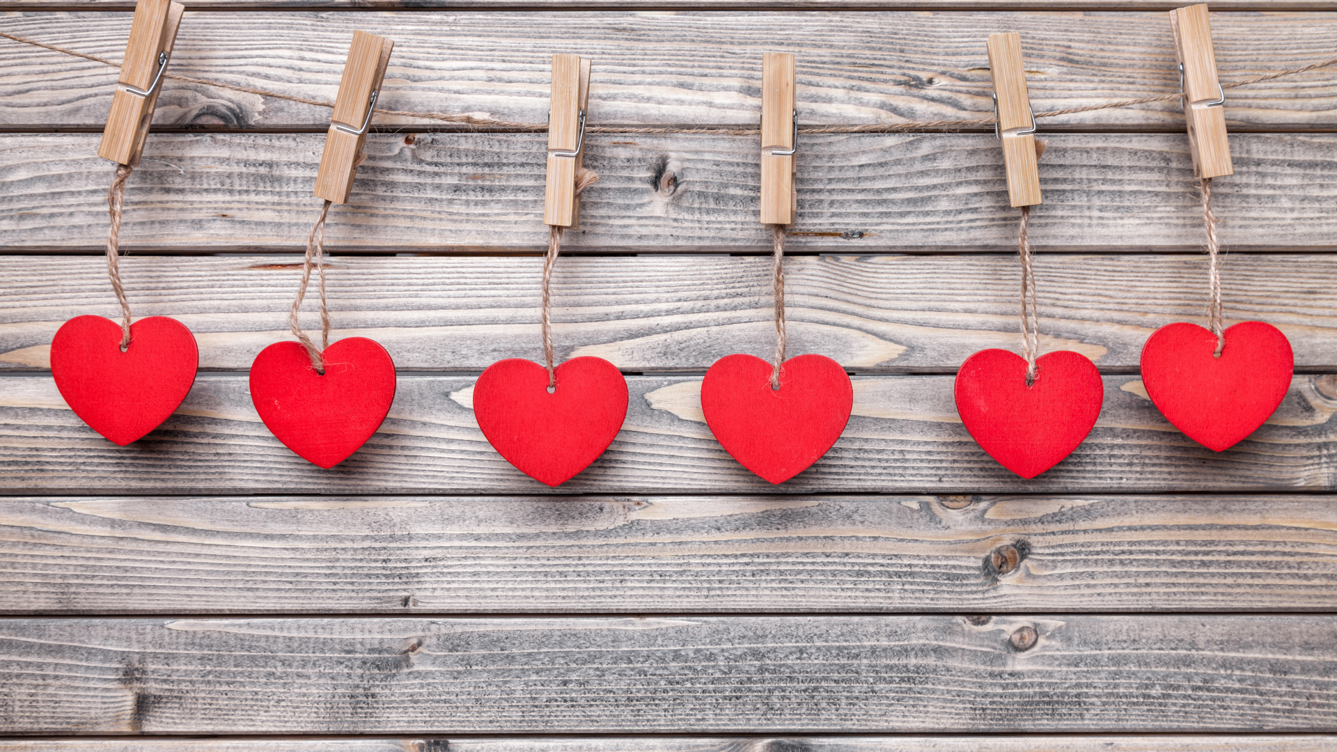 Красные сердечки на прищепках на деревянном столе 