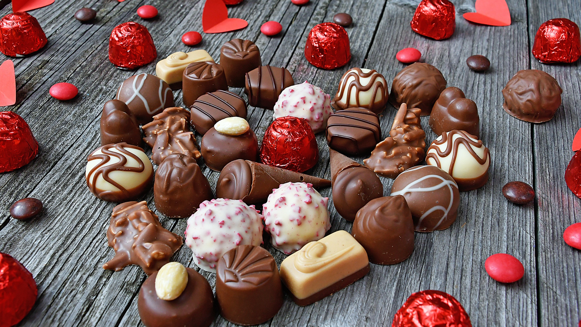 Сладкое сердце из шоколадных конфет на деревянном столе