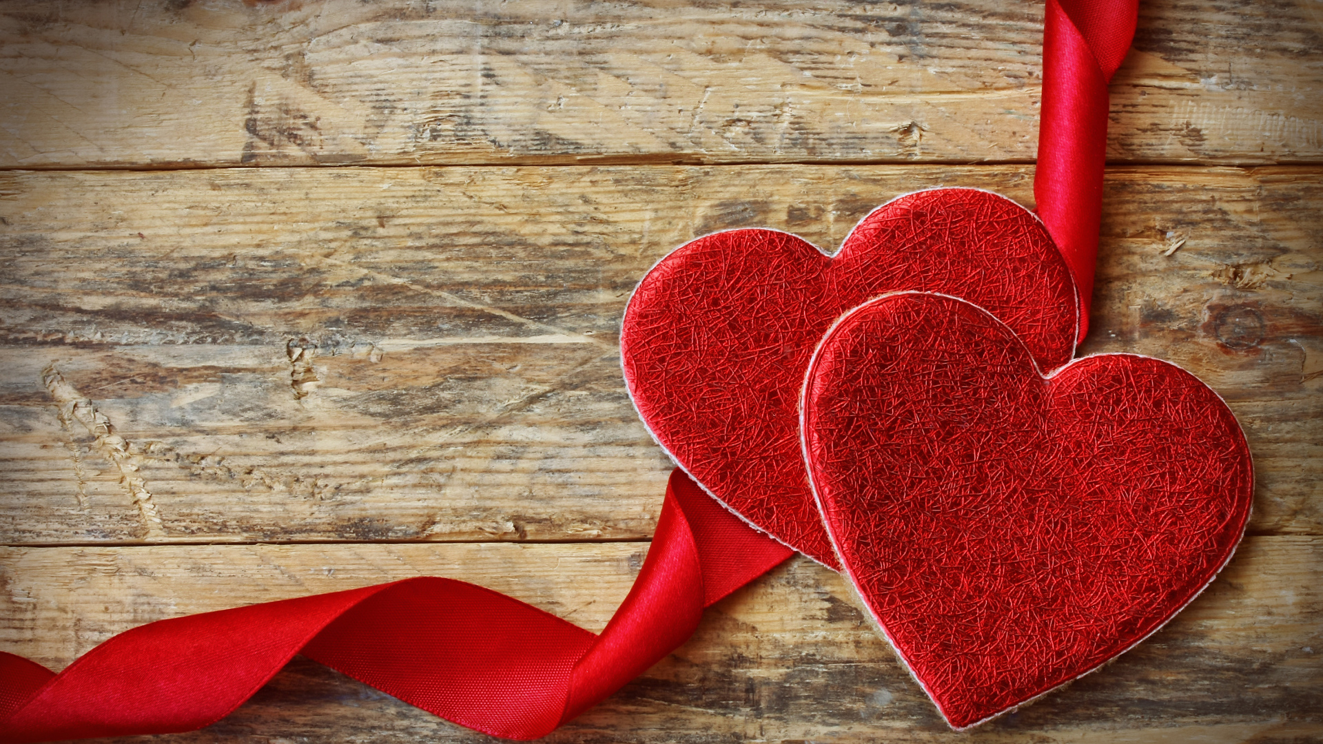 Два сердца с красной лентой на деревянном столе