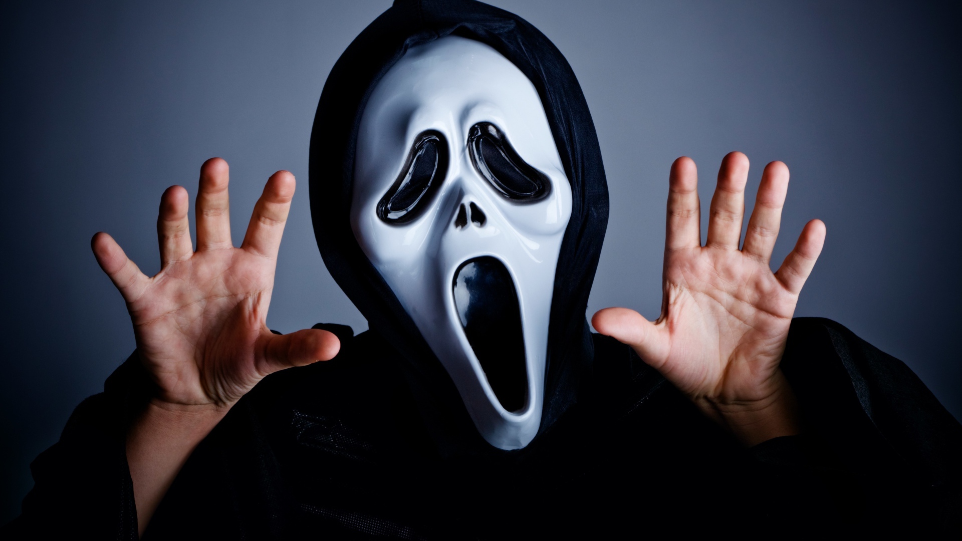 Мужчина в маске пугает на сером фоне