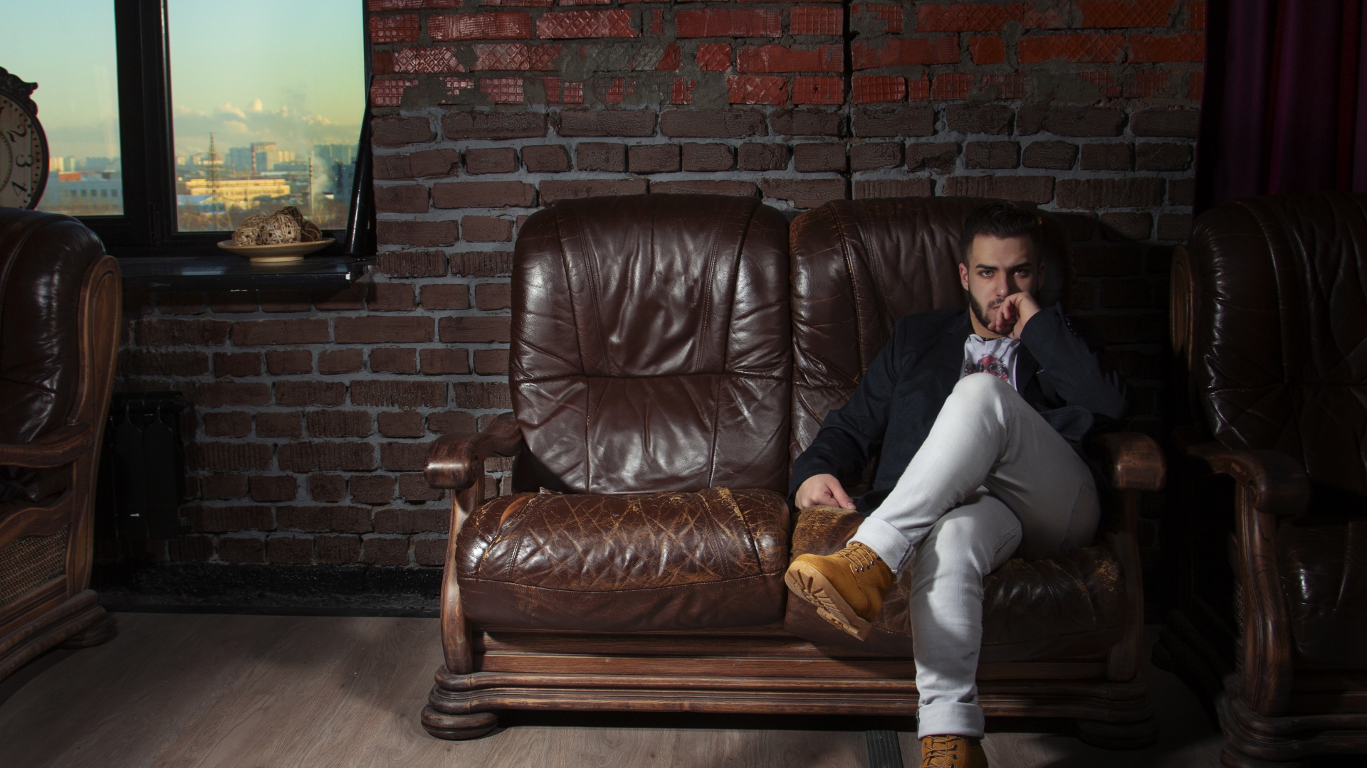 Стильный мужчина сидит в кожаном кресле 