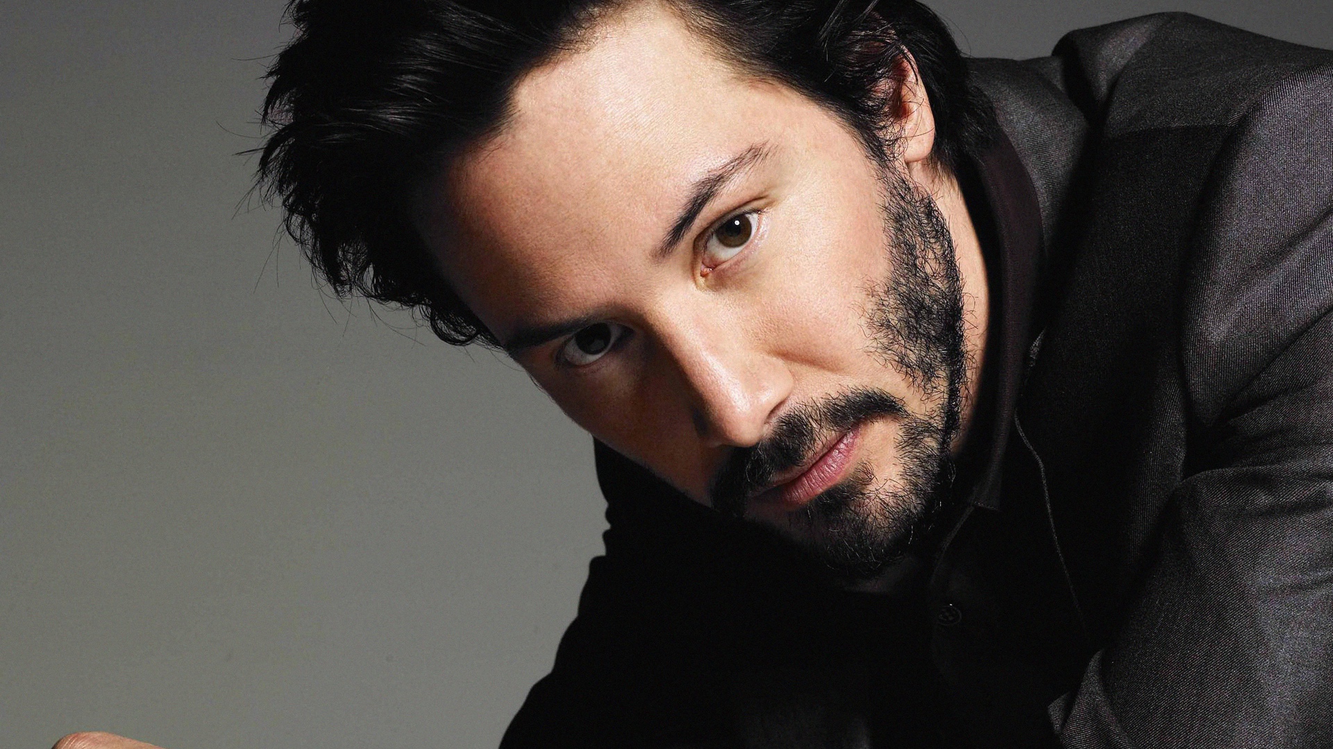 Актер Киану Ривз в костюме на сером фоне