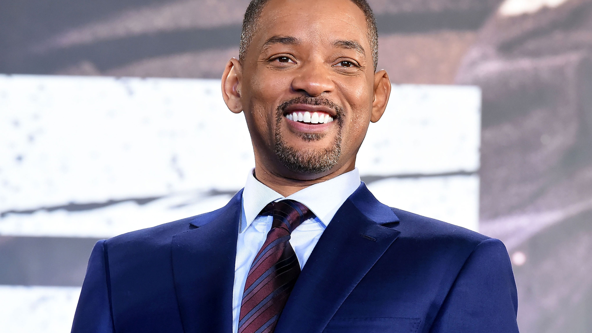 Улыбающийся мужчина в костюме, актер Уилл Смит 