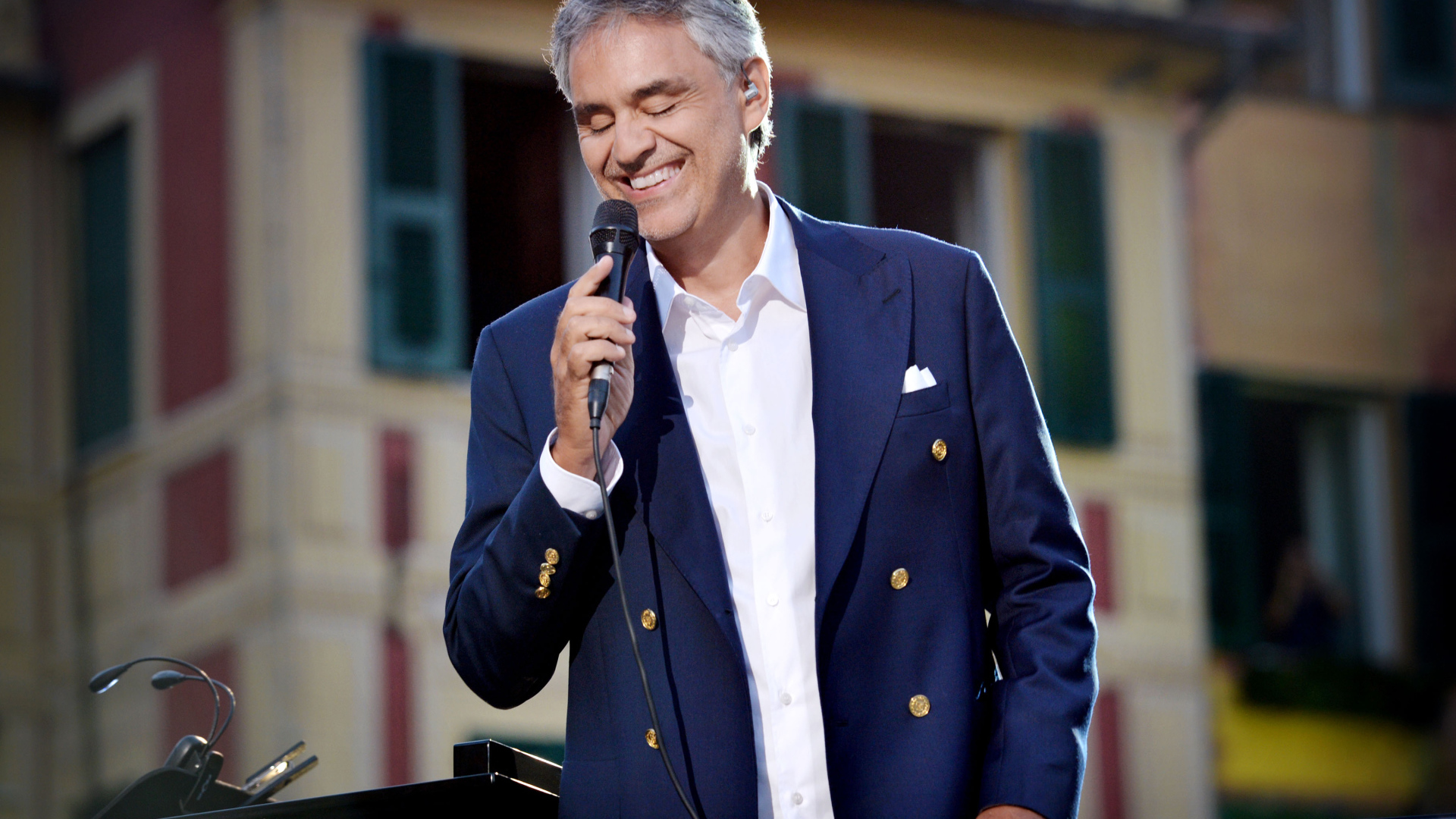 Итальянский певец Андреа Бочелли в костюме с микрофоном