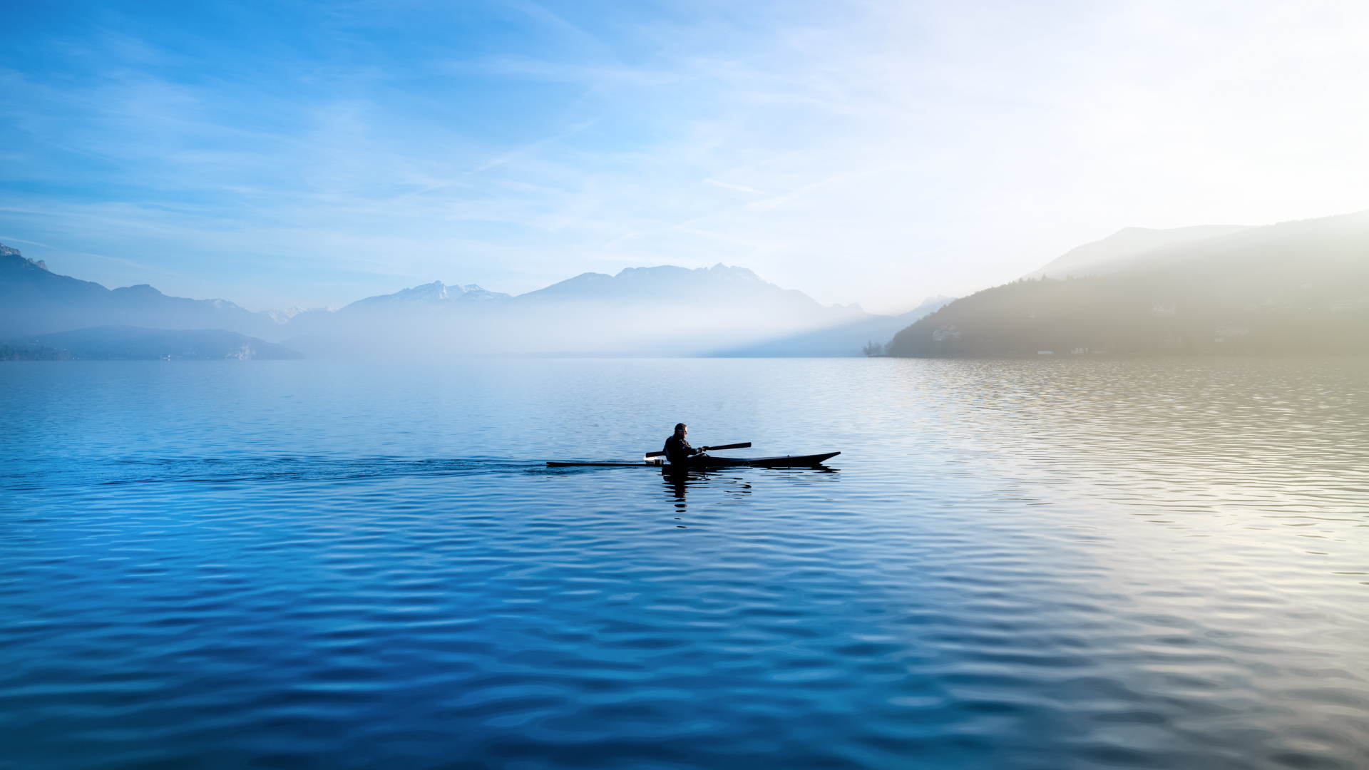 Мужчина плывет на лодке на фоне гор