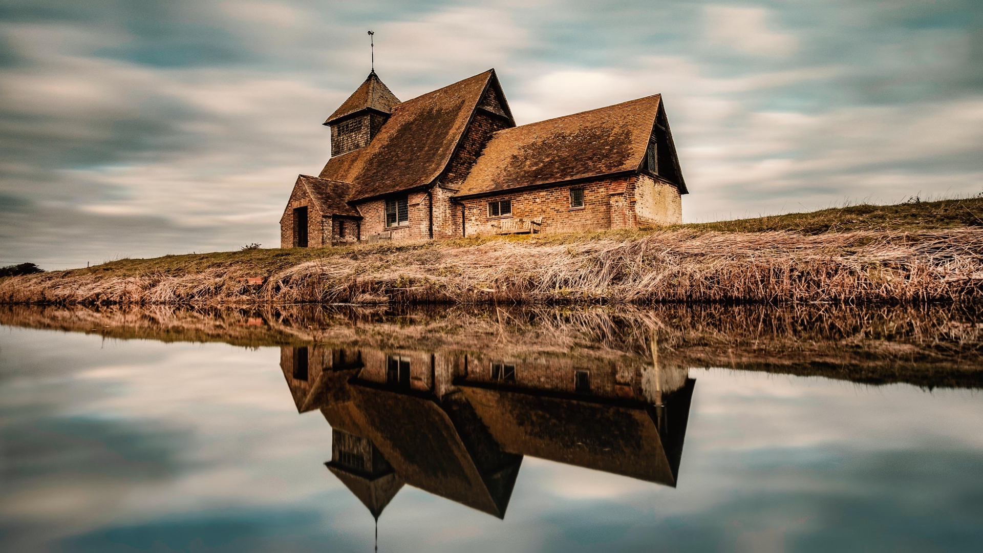 An old house by the river is reflected in the water