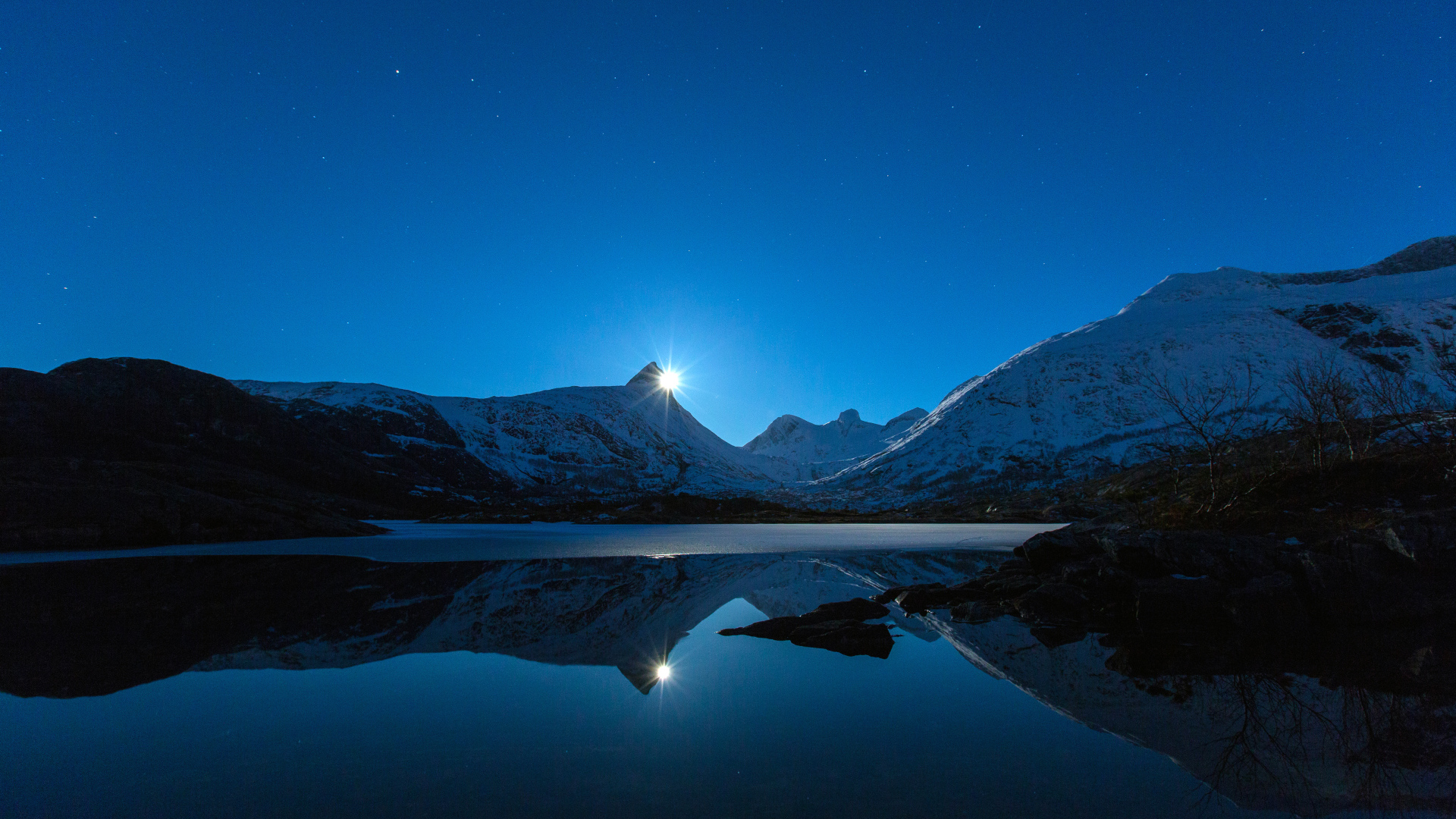 Луна и заснеженные горы отражаются в воде 