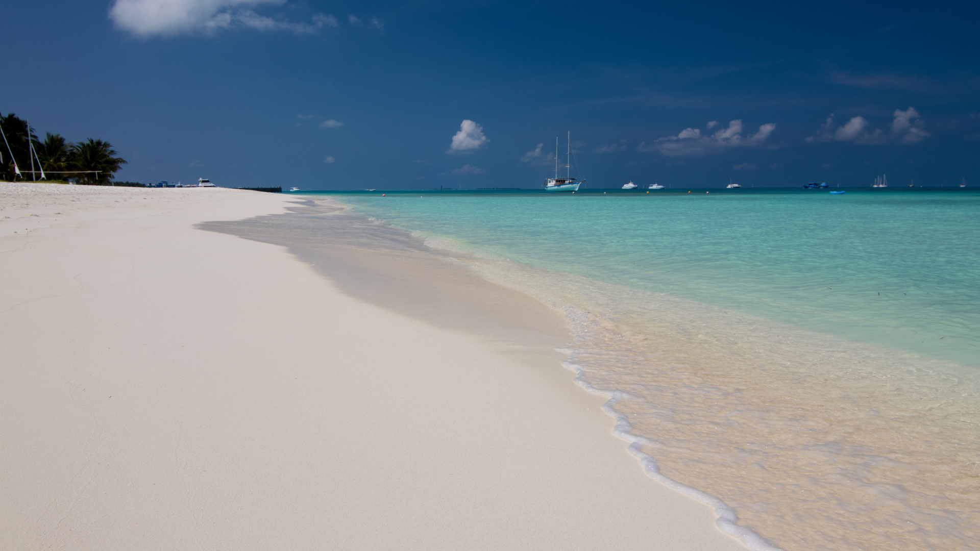 Спокойные волны на белом горячем песке под голубым небом