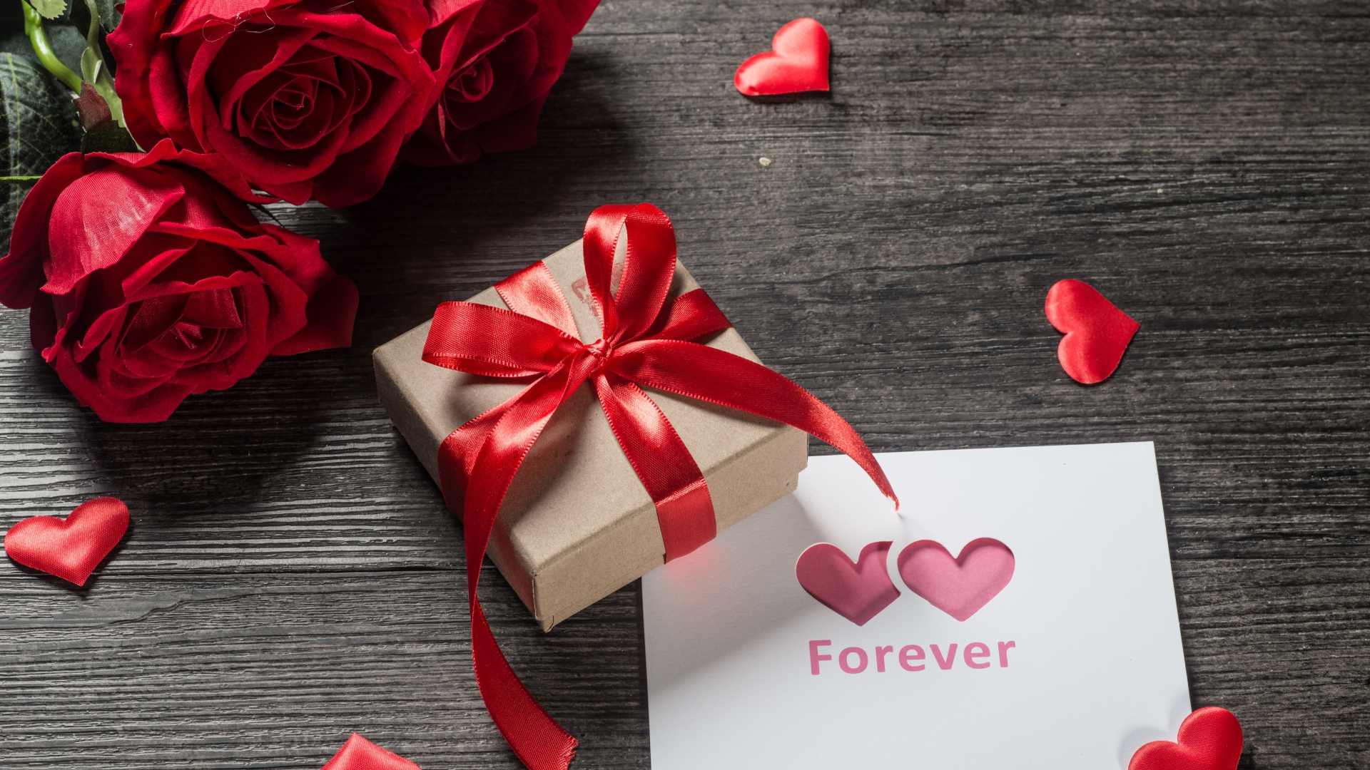 Букет красных роз с подарком и открыткой на столе